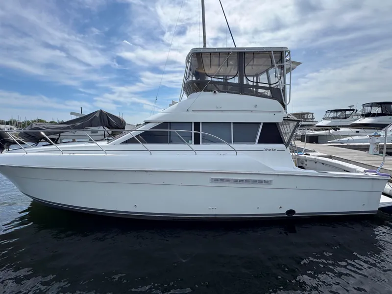 Slide: The Image of 1997 Silverton 41 Convertible yacht docked at marina under cloudy sky. - 2