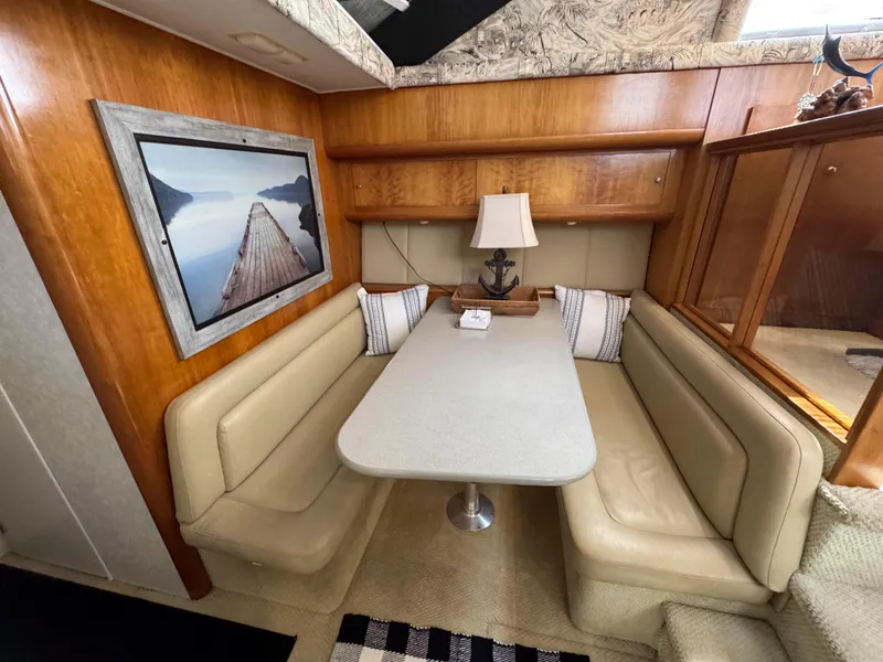 Slide: The Image of 1997 Silverton 41 Convertible interior with dining area, beige seating, and wall art. - 25
