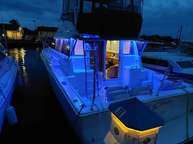 Slide: The Image of 1997 Silverton 41 Convertible yacht with blue LED lights docked at night. - 5