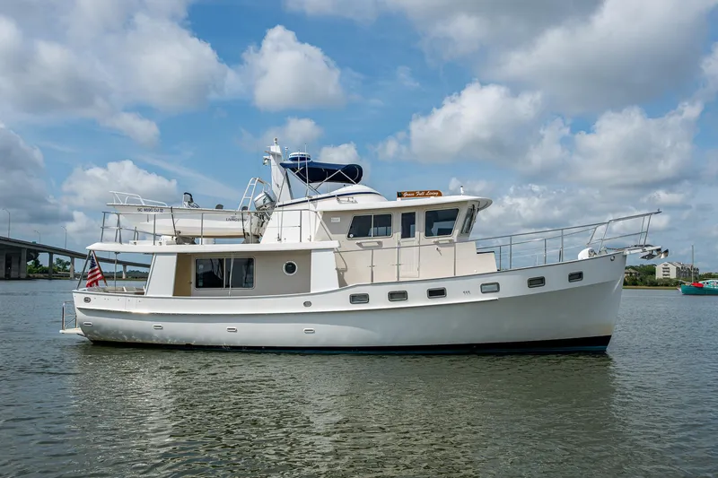 Slide: The Image of Kadey-Krogen 48 North Sea yacht, 2000 model, cruising on a calm waterway under a cloudy sky. - 2