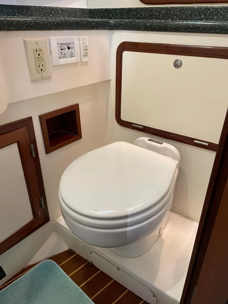Slide: The Image of Boat bathroom with toilet, wooden accents, and storage. Outbound 44, year 2000. - 31