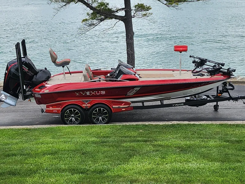 Slide: The Image of 2020 Vexus VX20 red boat on trailer by a lake, showcasing sleek design and modern features. - 0