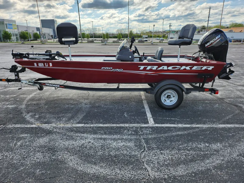 Slide: The Image of 2022 Tracker Pro 170 boat on trailer in parking lot, red exterior, overcast sky. - 11