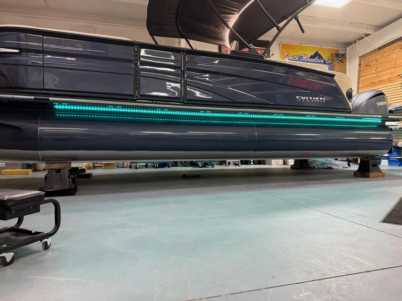 Slide: The Image of 2025 Sylvan G-3 CLZ DH pontoon boat with teal LED lights in a showroom. - 4