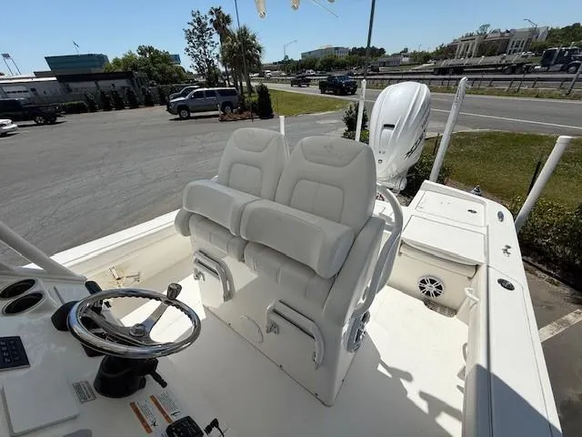 Slide: The Image of 2024 Regulator 26XO boat with dual white seats and steering wheel, parked outdoors. - 8