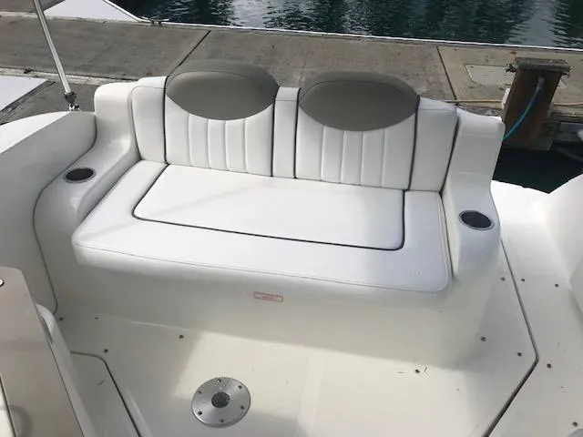 Slide: The Image of 2006 Sea Ray Sundancer boat seating with white cushions and cup holders, dockside view. - 11