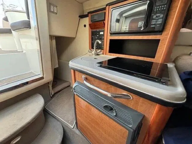 Slide: The Image of 2006 Sea Ray Sundancer interior with kitchenette, featuring microwave, sink, and stove. - 14