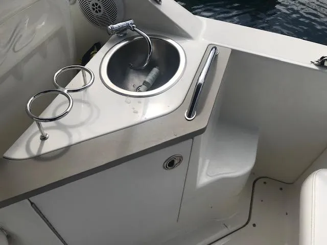Slide: The Image of 2006 Sea Ray Sundancer boat sink area with cup holders and stainless steel faucet. - 18