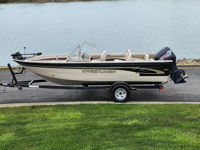 Slide: The Image of 2000 Crestliner 1850 Sportfish boat on trailer by a lake. - 0