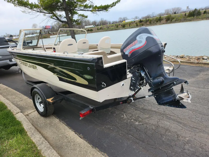 Slide: The Image of 2000 Crestliner 1850 Sportfish boat with outboard motor on trailer by a lake. - 1