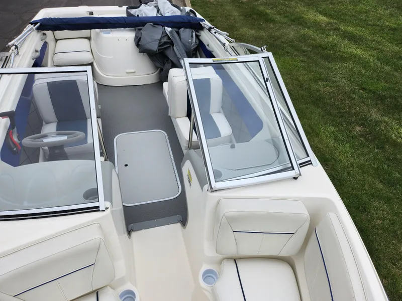 Slide: The Image of 2007 Bayliner Discovery 195 boat interior with open seating and windshield, parked on grass. - 18
