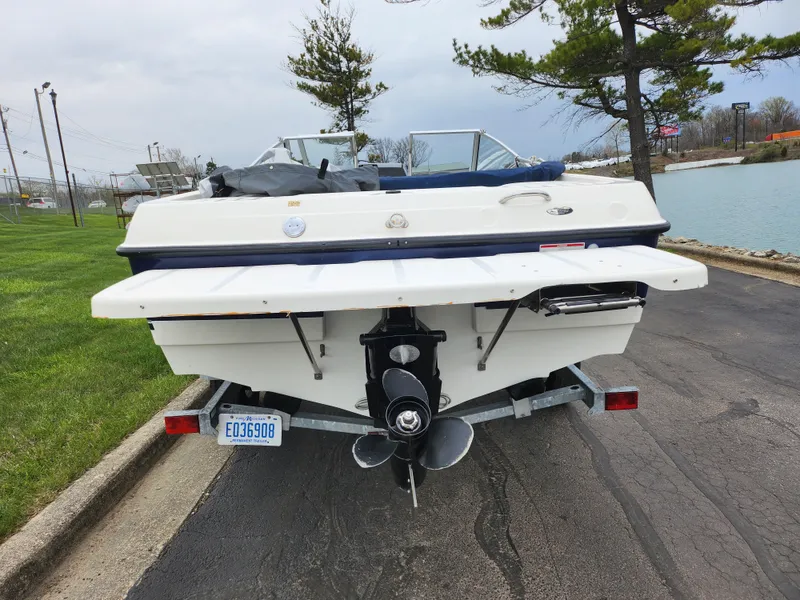 Slide: The Image of 2007 Bayliner Discovery 195 boat on trailer, rear view near a lake. - 2