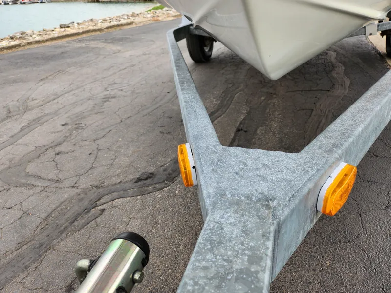 Slide: The Image of Trailer for 2007 Bayliner Discovery 195 boat on a paved surface near water. - 7