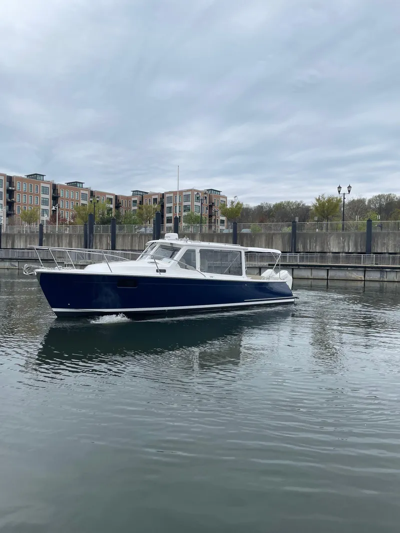 Slide: The Image of 2025 MJM 35 boat cruising in a calm marina with modern buildings in the background. - 12