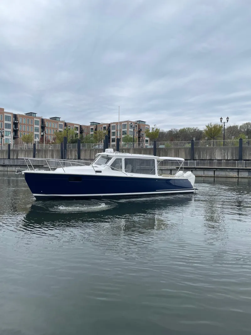 Slide: The Image of 2025 MJM 35 boat cruising on calm water near urban buildings. - 13