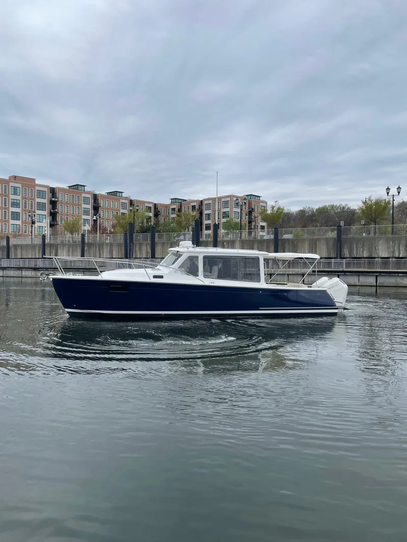 Slide: The Image of 2025 MJM 35 boat cruising in a calm urban waterway, overcast sky. - 14