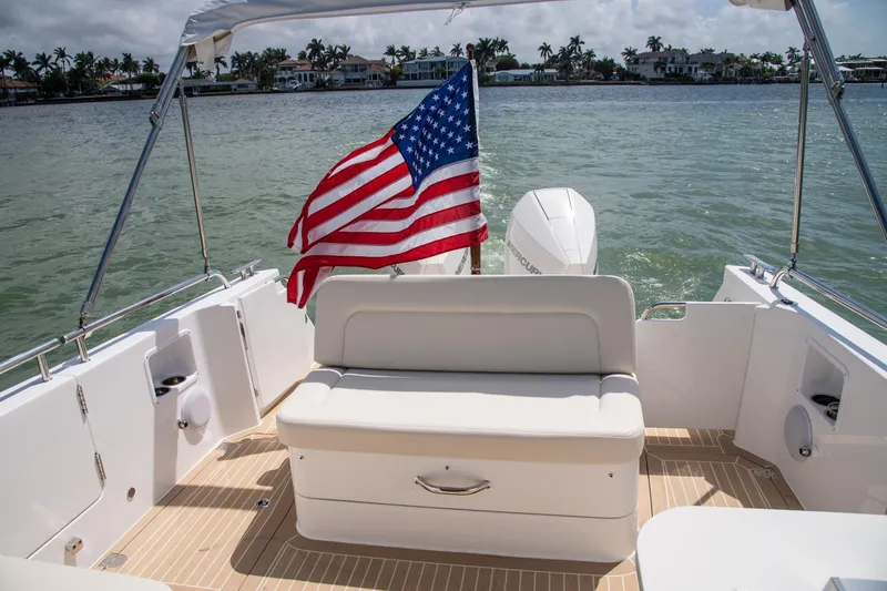 Slide: The Image of 2025 MJM 35 boat with American flag, rear seating, and scenic waterfront view. - 17