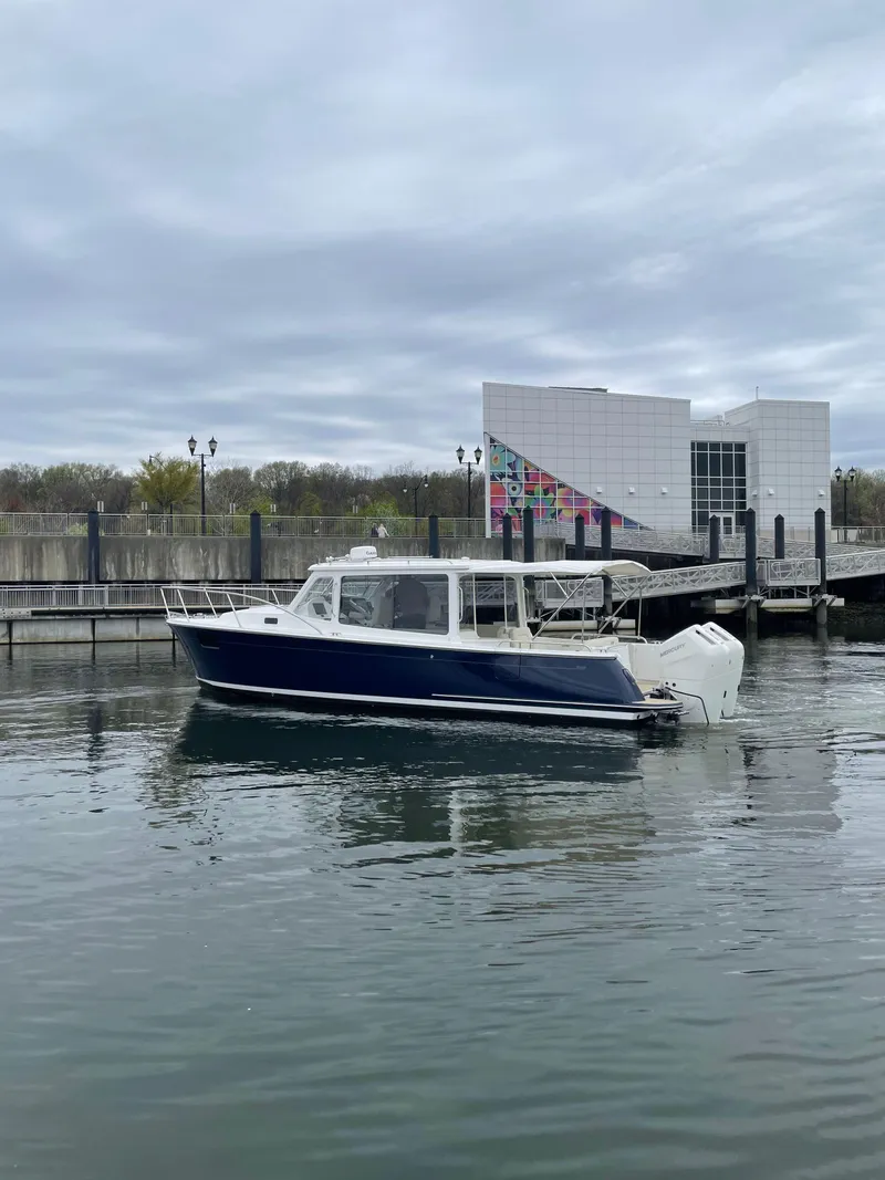 Slide: The Image of 2025 MJM 35 boat docked in a marina with modern building backdrop. - 2