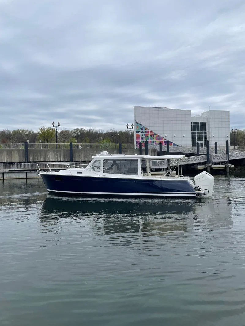 Slide: The Image of 2025 MJM 35 boat docked near modern waterfront building under cloudy sky. - 3