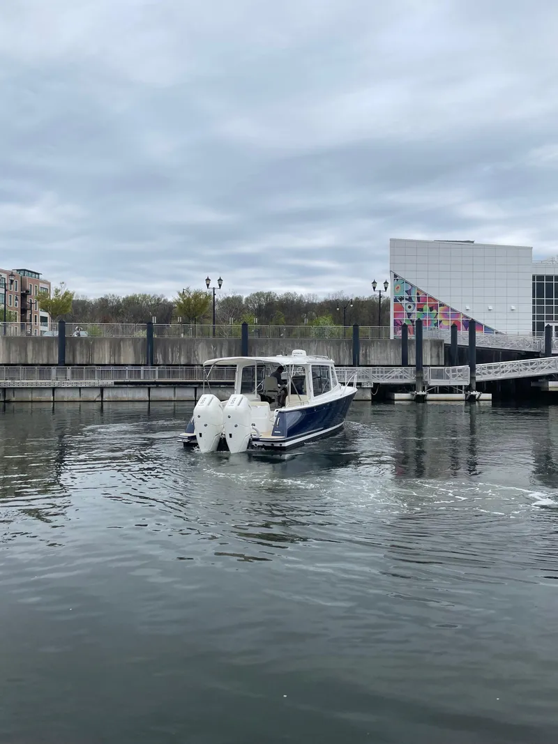 Slide: The Image of 2025 MJM 35 boat cruising in a marina with modern architecture in the background. - 5
