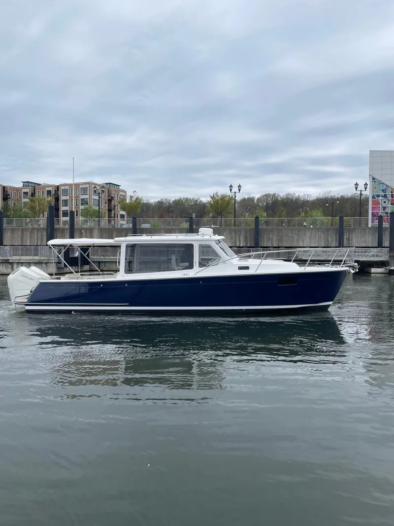 Slide: The Image of 2025 MJM 35 boat docked on calm water, with modern buildings in the background. - 7