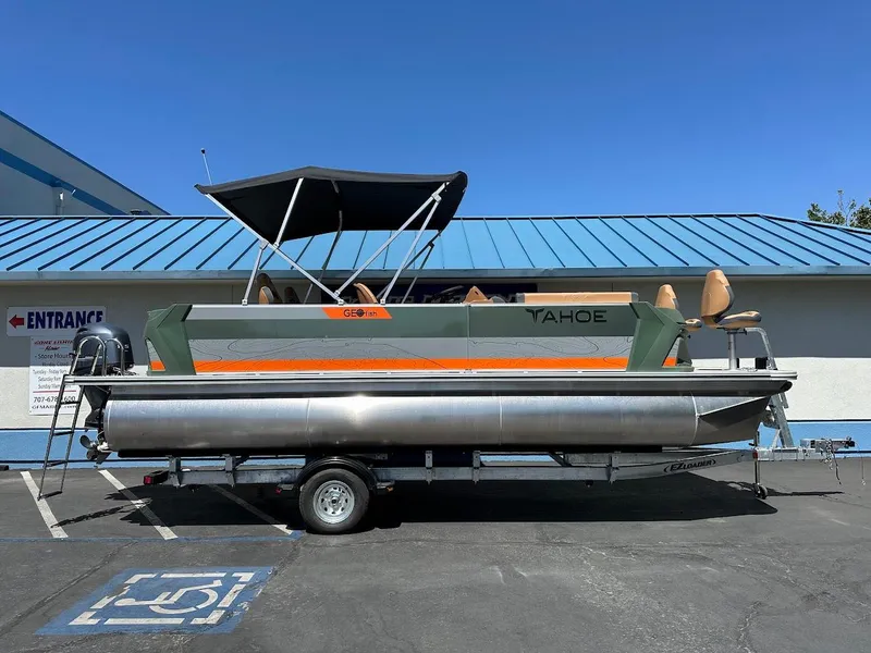 Slide: The Image of 2025 Tahoe Pontoon Geofish RF boat on trailer, parked in sunny lot. - 0