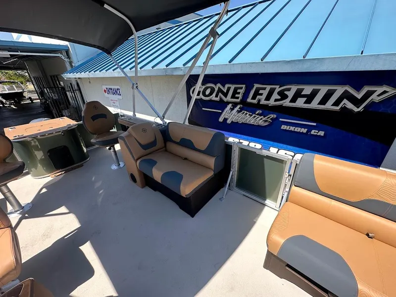 Slide: The Image of 2025 Tahoe Pontoon Geofish RF interior with tan and gray seating, under a blue canopy. - 13