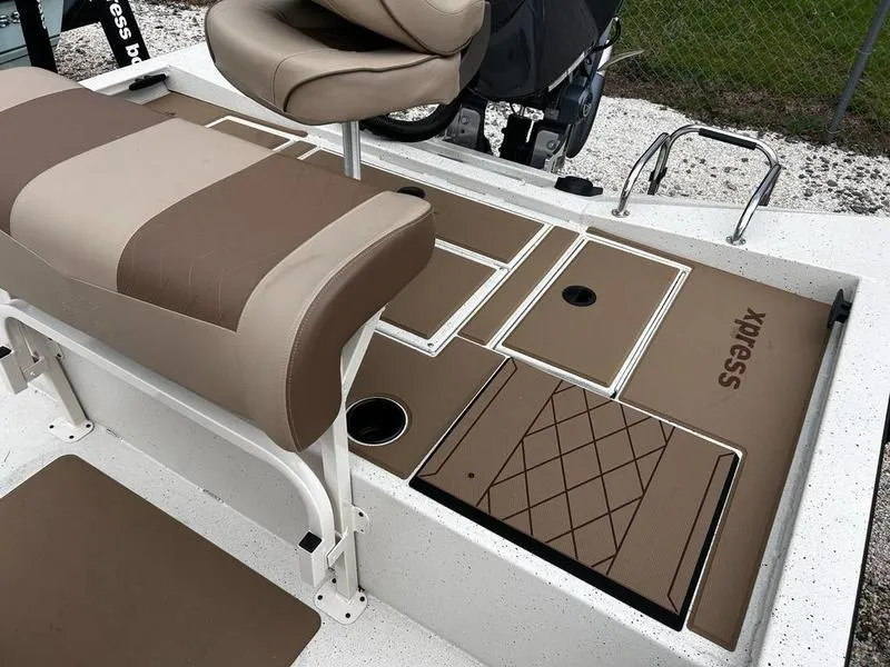 Slide: The Image of 2025 Xpress H210B boat interior with tan and brown seating and storage compartments. - 7