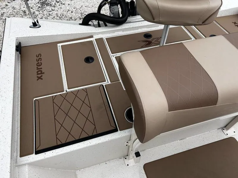 Slide: The Image of 2025 Xpress H210B boat interior with brown cushioned seating and storage compartments. - 9