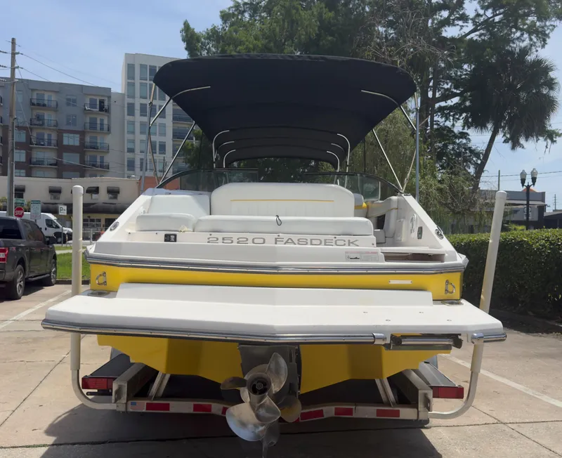 Slide: The Image of 2008 Regal 2520 FasDeck boat with canopy, parked on a trailer in an urban setting. - 4