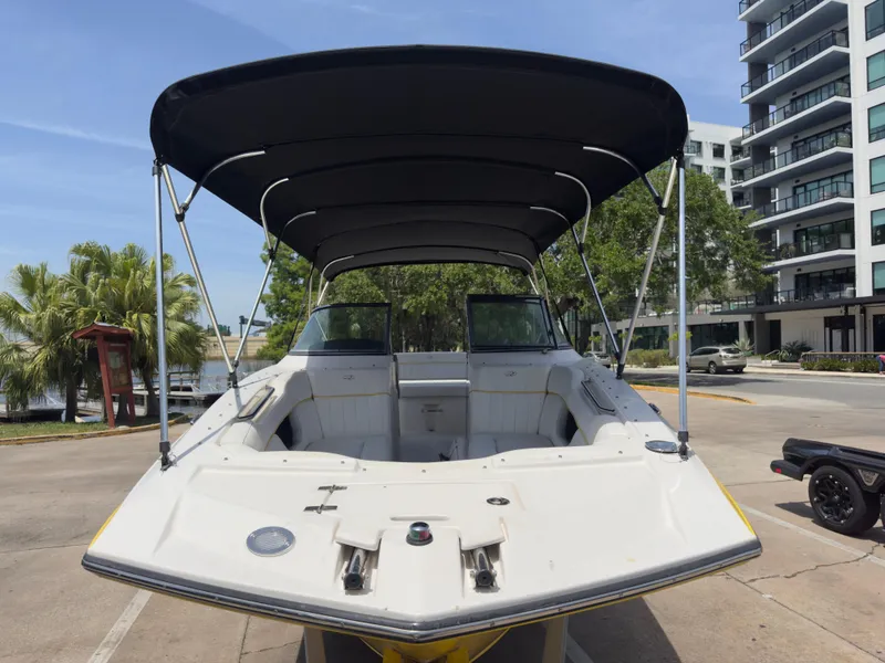 Slide: The Image of 2008 Regal 2520 FasDeck boat with canopy, docked near modern buildings and palm trees. - 5