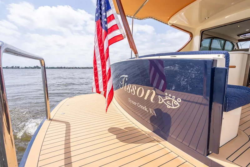 Slide: The Image of 2018 Palm Beach Motor Yachts PB45 with American flag on deck, cruising on open water. - 10