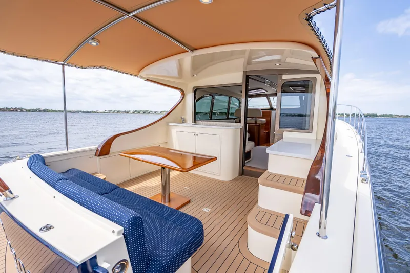 Slide: The Image of 2018 Palm Beach Motor Yachts PB45, elegant deck with seating and table, overlooking serene waters. - 11