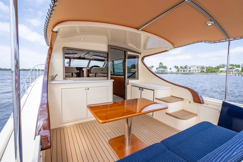 Slide: The Image of 2018 Palm Beach Motor Yachts PB45 interior with wooden table, seating, and waterfront view. - 12