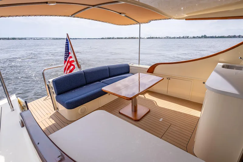 Slide: The Image of 2018 Palm Beach Motor Yachts PB45 deck with seating, table, and ocean view. - 14