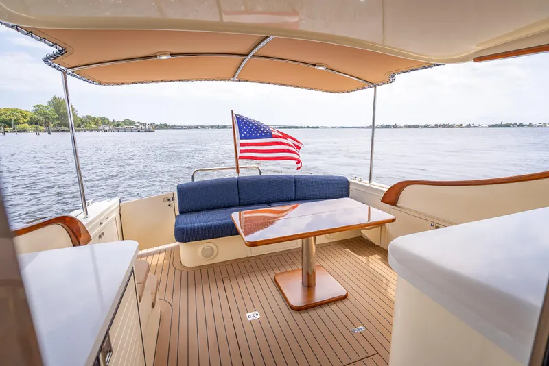 Slide: The Image of 2018 Palm Beach Motor Yachts PB45 interior with American flag, wooden deck, and seating area. - 15