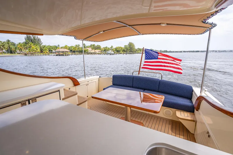 Slide: The Image of 2018 Palm Beach Motor Yachts PB45, elegant deck with seating, American flag, scenic water view. - 16