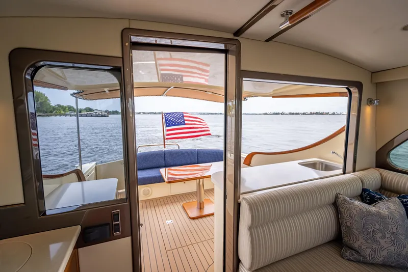 Slide: The Image of 2018 Palm Beach Motor Yachts PB45 interior with American flag, elegant seating, and scenic water view. - 25