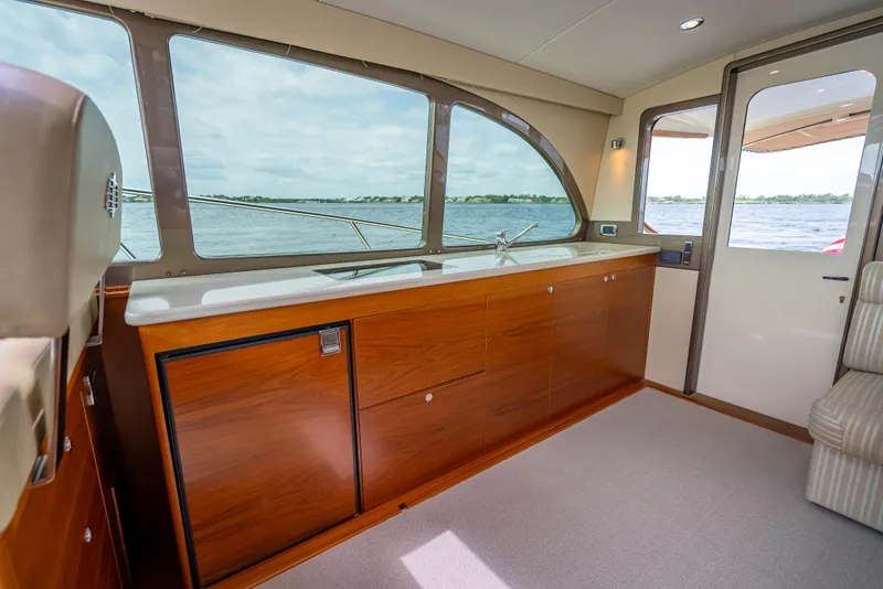 Slide: The Image of 2018 Palm Beach Motor Yachts PB45 interior with wooden cabinetry and large windows overlooking the water. - 34