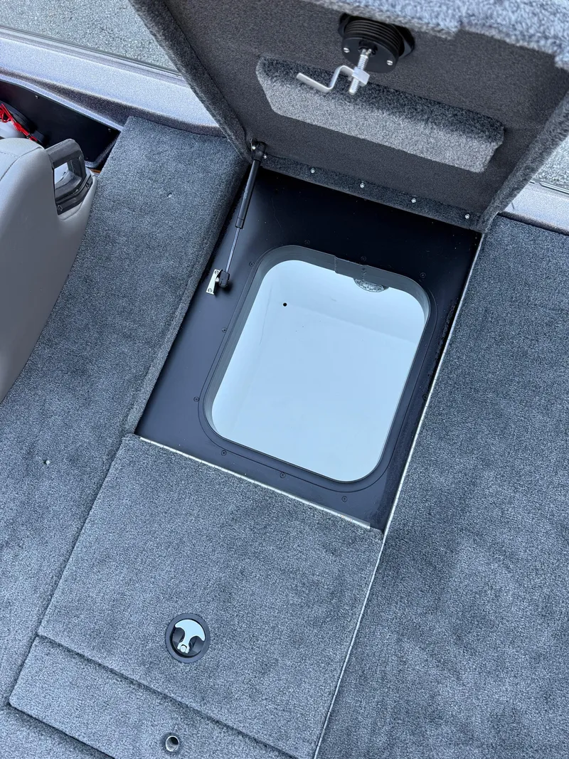 Slide: The Image of 2025 Skeeter ZXR 20 SE boat storage compartment with open hatch and gray carpet. - 23