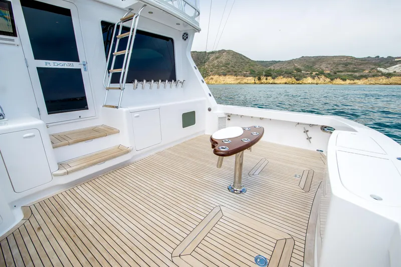 Slide: The Image of 2003 Donzi R65 yacht deck with wooden flooring, ocean view, and fishing rod holders. - 2