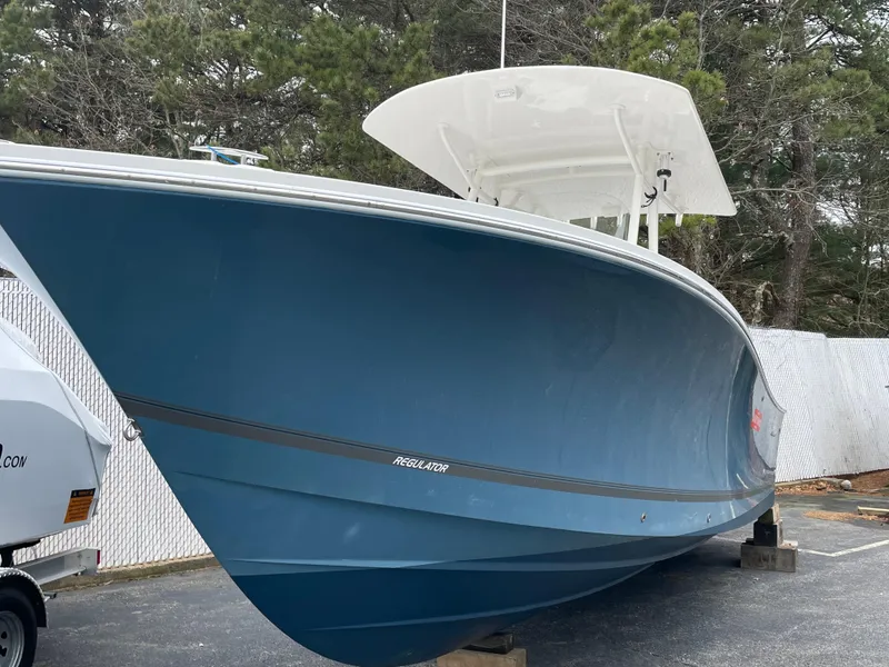 Slide: The Image of 2016 Regulator 28 boat with blue hull, parked outdoors on a paved surface. - 0