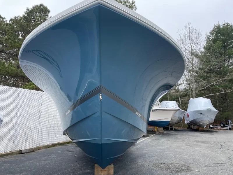 Slide: The Image of 2016 Regulator 28 boat with blue hull, parked outdoors on a cloudy day. - 2