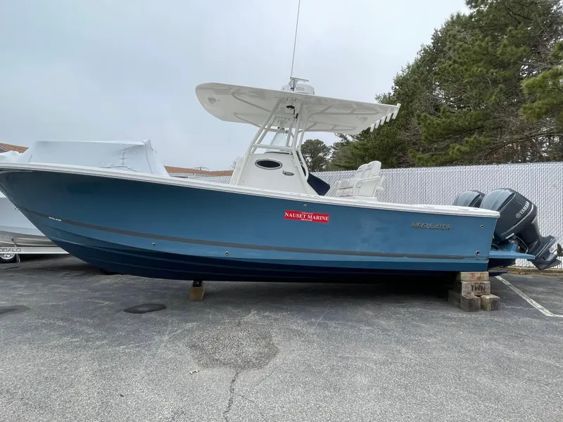 Slide: The Image of 2016 Regulator 28 boat with blue hull, parked on blocks, featuring twin engines. - 3