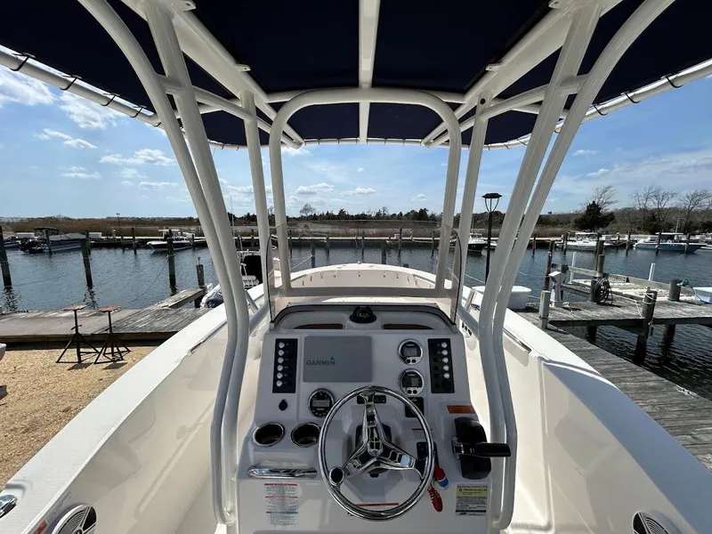 Slide: The Image of 2019 Robalo R202EX boat console with steering wheel, docked at marina under blue sky. - 15