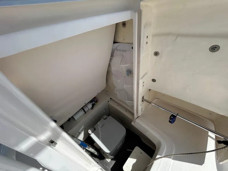 Slide: The Image of 2019 Robalo R202EX boat interior with compact toilet and storage area. - 18