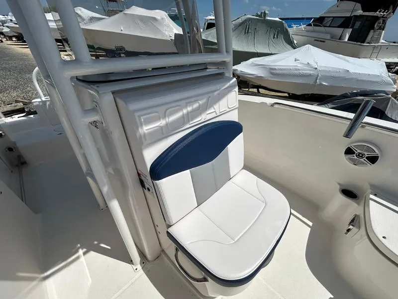 Slide: The Image of 2019 Robalo R202EX boat seat with blue and white upholstery, docked near covered boats. - 19