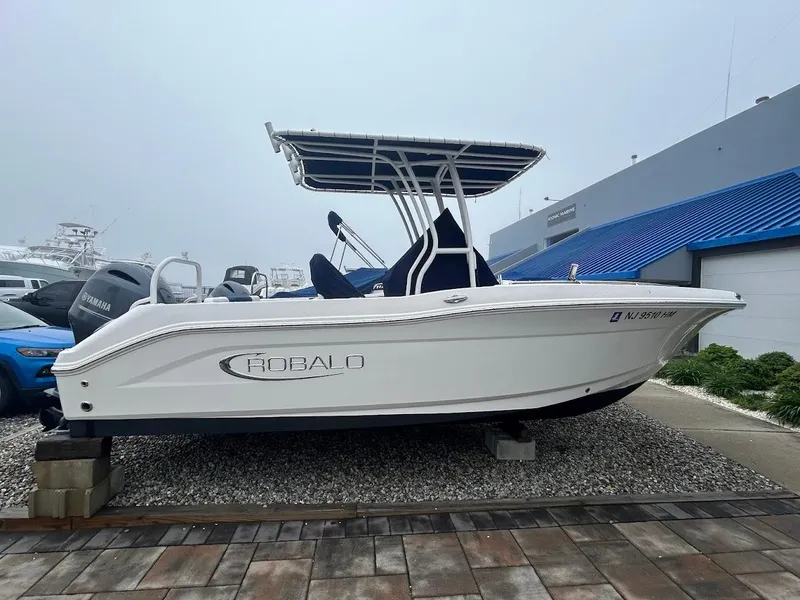 Slide: The Image of 2019 Robalo R202EX boat displayed outdoors on gravel. - 22