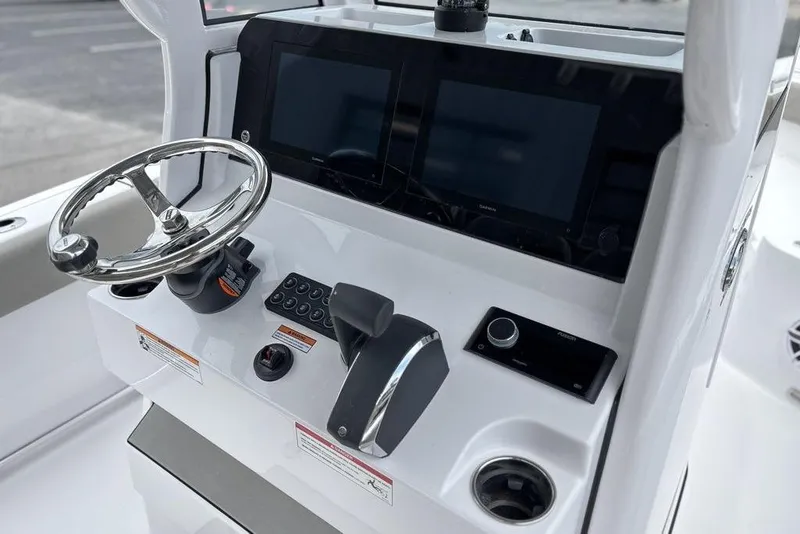 Slide: The Image of Control panel of 2025 Sportsman Heritage 231 boat with steering wheel and digital displays. - 14