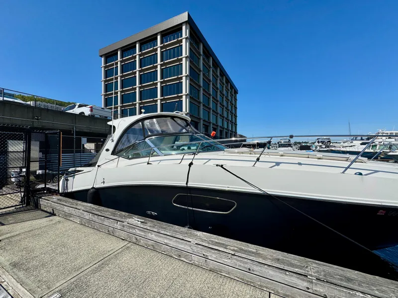 Slide: The Image of 2009 Sea Ray 350 Sundancer docked near a modern building under clear blue skies. - 2